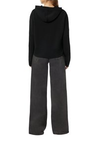 Czarna, krótkie hoodie z kapturem na sznurku, w połączeniu z luźnymi, ciemnoszarymi spodniami z szerokim nogawkami. Wykonana z miękkiego materiału i charakteryzująca się minimalnymi detalami w szyciu.