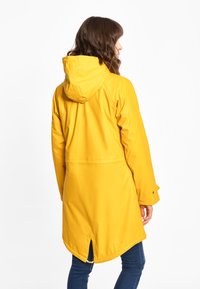 Cappotto antipioggia giallo impermeabile con cappuccio, maniche lunghe e aperture laterali. Finitura liscia, lunghezza fino al ginocchio con orlo curvo e polsini con bottoni.