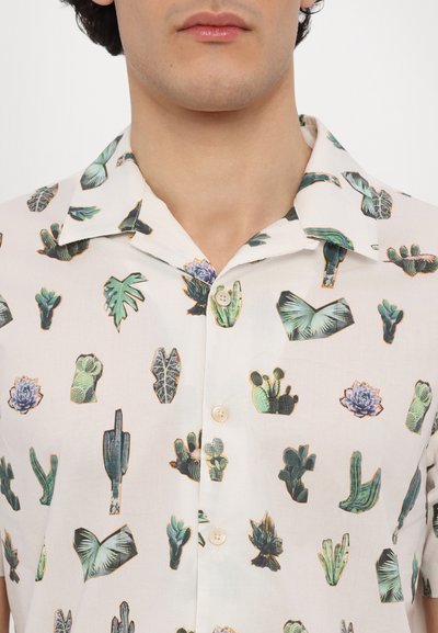 Camisa de manga corta con un fondo crema claro y varios estampados vibrantes de cactus y suculentas. Hecha de una tela ligera con un cuello tipo polo.