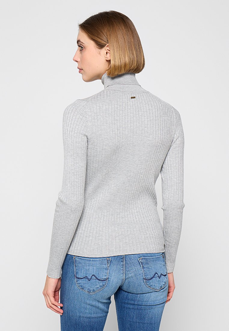 Grijze geribbelde coltrui met lange mouwen, voorzien van een subtiele accent aan de achterkant van de hals, gecombineerd met een blauwe jeans met gestikte details.