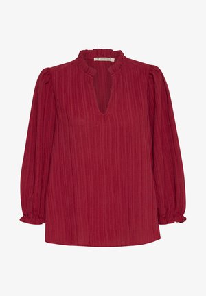 Blouse rouge texturée avec un col en V et un encolure froncée. Manches longues avec des poignets élastiques, présentant de légères lignes verticales et une coupe ample.