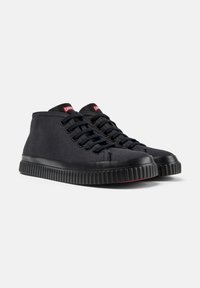 High-top sneakers made of black fabric with a textured finish. Features black rubber sole with ribbed edges and red branding on the tongue.