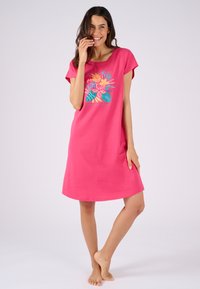 Abito di cotone rosa con maniche corte, caratterizzato da una stampa tropicale colorata sul petto. Vestibilità comoda e ampia, lunghezza fino al ginocchio.