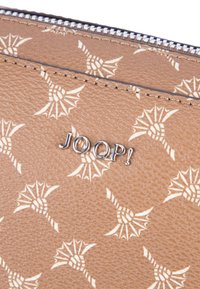Portafoglio in pelle marrone con un motivo sottile di fiori stilizzati e un logo "JOOP!" in tono argento. Chiusura a cerniera lungo il bordo superiore.