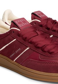 Donkerrood sneakers met een bovenwerk van textuurrijk suède en gladde stof, voorzien van logo-accenten, een gevoerde tong en een bruine rubberen buitenzool.