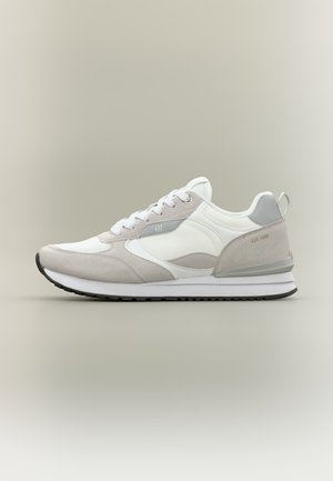 Baskets blanches et gris clair avec des lacets blancs, une semelle grise, un logo "GAP" sur le côté et le texte "EST. 1969" sur le talon.