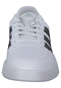 White athletic shoe featuring a smooth leather upper, three black stripes on the side, and a textured sole with rounded edges.