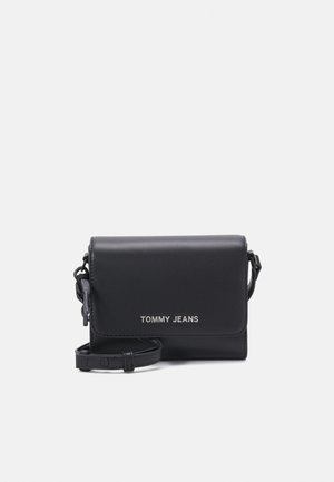 Zwarte Tommy Jeans crossbodytas met klep en verstelbare riem op een witte achtergrond.