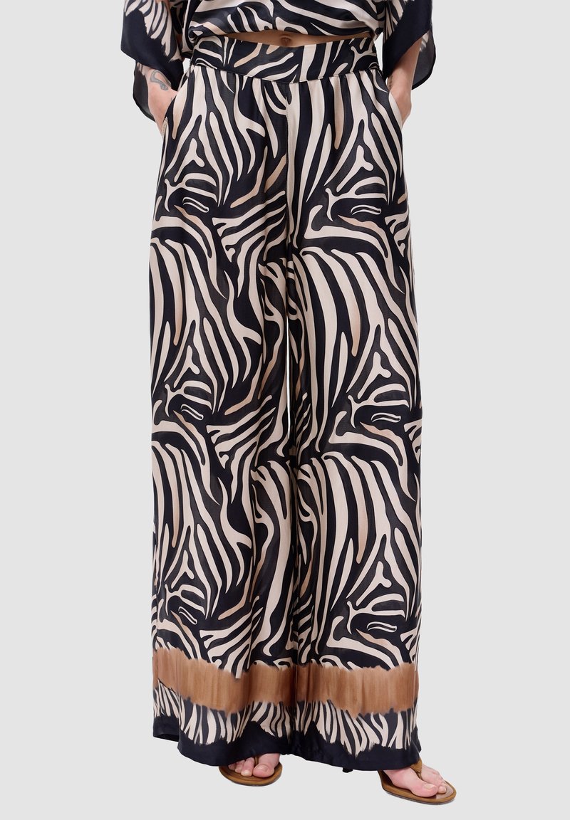 Brede pijpen in zwart en beige zebra print. Gemaakt van gladde stof met een gevlochten tailleband en een bruine verloopaccent aan de zoom.