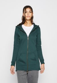 Sudadera con cremallera larga en color verde azulado, hecha de un tejido suave, que cuenta con una cremallera frontal, capucha y dos bolsillos frontales. Acentuada con herrajes dorados.
