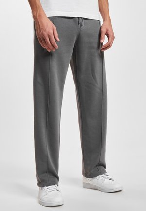 Grå joggebukser laget av et mykt stoff, med snor i livet, sidesømmer og en avslappet passform, kombinert med hvite sneakers.