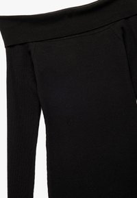 Zwarte off-the-shoulder top met lange mouwen, gemaakt van ribgebreide stof, met een aansluitende snit en naadloze halslijn.