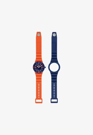 Deux montres-bracelets en silicone posées à plat : une orange avec cadran bleu affichant l'heure, une bleue avec un boîtier vide. Les deux ont des boutons métalliques sur les bracelets.