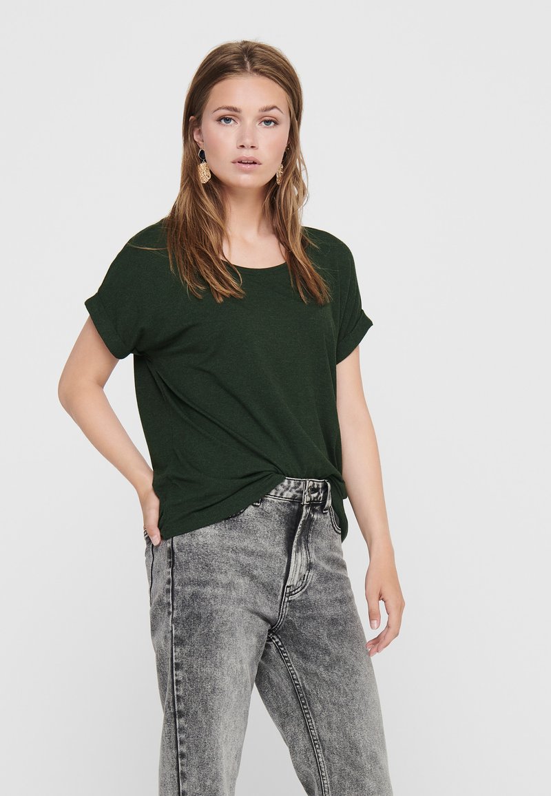 Ciemnozielony t-shirt z krótkim rękawem i okrągłym dekoltem. W połączeniu z poszarpanymi, szarymi spodniami z wysokim stanem. Luźny krój i miękka tekstura.