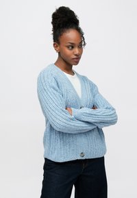 Cardigã azul claro em malha com decote em V e fecho de botões, com um design canelado texturizado e mangas compridas. Combina com jeans escuros.