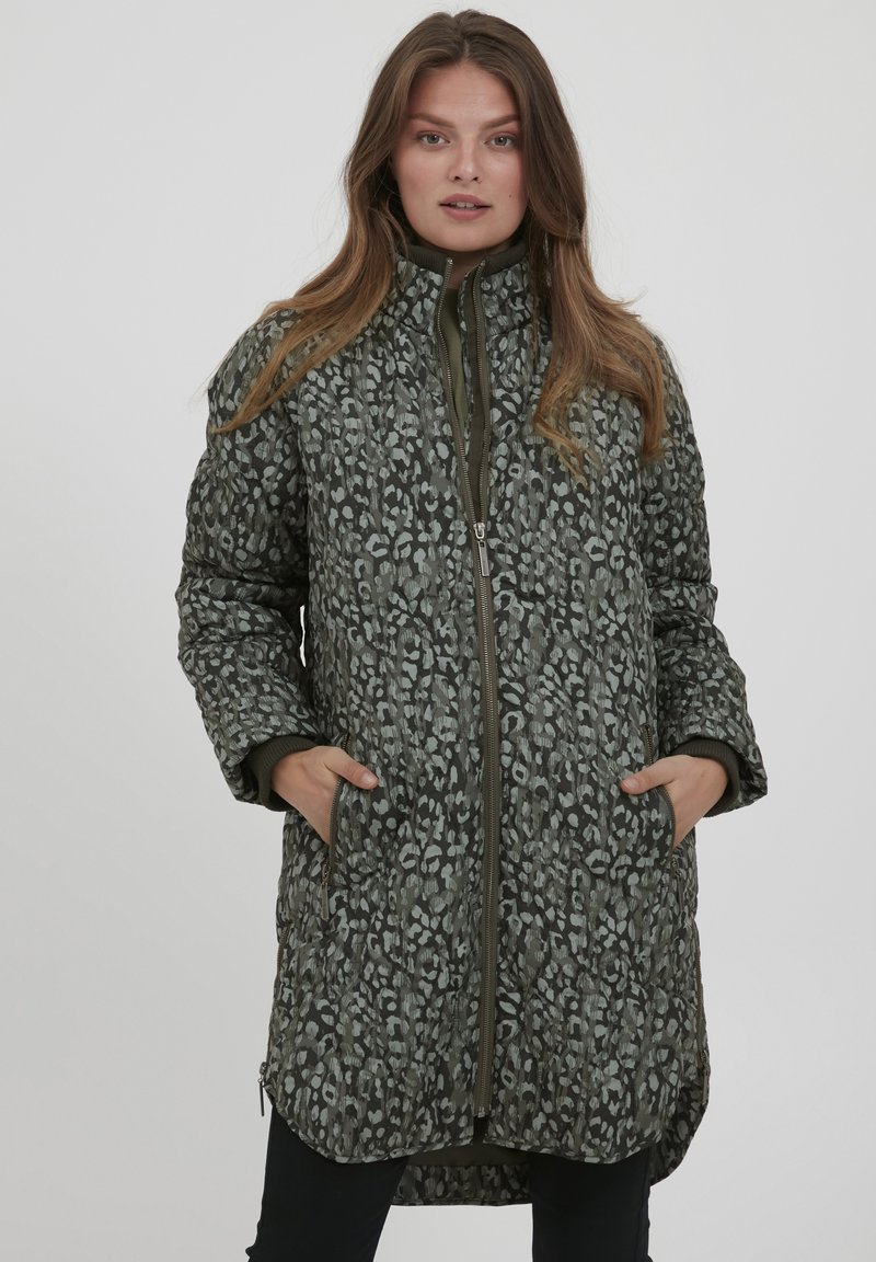 Zaļa quilted jaka ar leoparda rakstu, augstu apkakli un rāvējslēdzēja aizdari. Iespējamas sānu kabatas un garāks apakšmalas garums aizmugurē.
