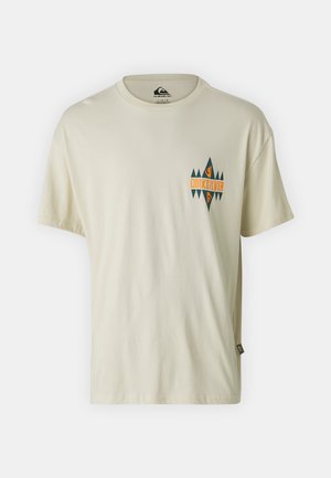 Kremfarget T-skjorte laget av bomull, med et geometrisk Quiksilver-logo i oransje og mørkegrønt på venstre bryst. Rund hals.