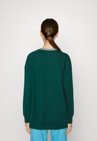 Dark green sweatshirt with long sleeves, rounded neck, and contrasting white stripe along collar. Soft texture, relaxed fit, and ribbed cuffs.