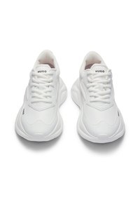 Valkoiset tennarit, jossa verkkomainen materiaali, pyöreä kärki, kuvioitu pohja ja "HUGO"-brändäys kielekkeessä ja sivulla. Nauhallinen kiinnitys.