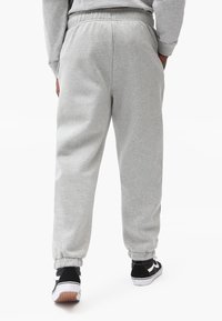 Gray sweatpants made of soft fabric with an elastic waistband, cuffed ankles, and side pockets, paired with black sneakers.