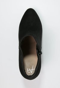 Stivale alla caviglia in suede nero con punta affusolata e zip laterale, caratterizzato da un interno liscio e un design minimalista.