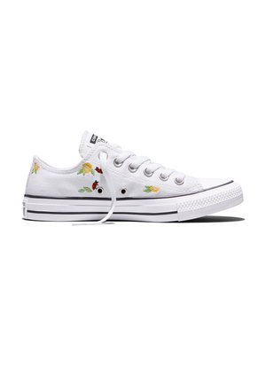 Zapatilla blanca de lona de corte bajo con flores amarillas bordadas y mariquitas, cordones blancos y suela de goma blanca con rayas negras.