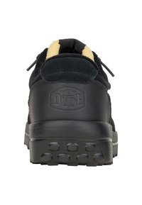 Baskets noires en daim et cuir, avec un col rembourré, des accents jaunes, une semelle en caoutchouc texturée et un logo "HEY DUDE" en relief à l'arrière.
