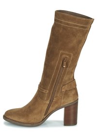 Botte haute en daim marron avec une tige incurvée, une fermeture éclair latérale, des coutures décoratives et un talon épais en bois. Elle présente une texture lisse et douce.