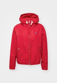 Czerwona kurtka z kapturem wykonana z lekkiego materiału. Posiada zamek błyskawiczny z przodu, dwie boczne kieszenie oraz białe sznurki. Mały niebieski logo na klatce piersiowej.
