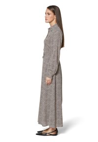 Maxi-jurk in een luipaardprint ontwerp, met een hoge kraag, lange mouwen en een vloeiende silhouet. Gecombineerd met zwarte flats.