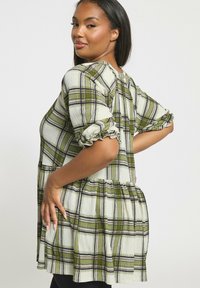 Blusa a quadri verde e bianca con maniche a sbuffo elasticizzate, vita arricciata e vestibilità ampia, con sottili accenti viola nel motivo.