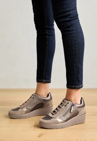 Zapatillas de cuero y ante en color beige con suela de cuña, que cuentan con un cierre lateral con cremallera, paneles texturizados y cordones.