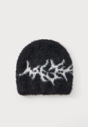 Sort fluffy hue med hvid lynmønster foran på en ensfarvet lys baggrund.