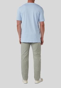Hellblauses Baumwoll-T-Shirt mit Rundhalsausschnitt, kombiniert mit hellgrauen Hosen und weißen Sneakers. Fokus auf lockerer Passform und weichem Stoffgefühl.