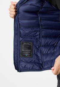 Navy down jacket interior, featuring quilted texture. Label indicates water-repellent and windproof properties. RDS certified down fill.