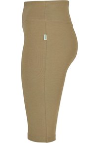Beige enkel-lange leggings van rekbaar materiaal, met een hoge tailleband en een klein merklabel aan de achterkant. Gladde textuur.