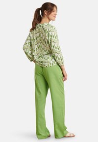 Floral-patterned green blouse with long sleeves paired with light green, loose-fitting pants. Soft fabric and relaxed silhouette.