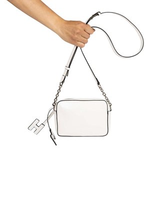 Bolso de cuero blanco cruzado con ribetes negros, forma rectangular, herrajes de cadena plateada y un llavero en forma de letra "H."