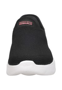 Zapatilla negra tipo slip-on Skechers GOWalk con suela blanca y parte superior de punto transpirable vista desde el frente.