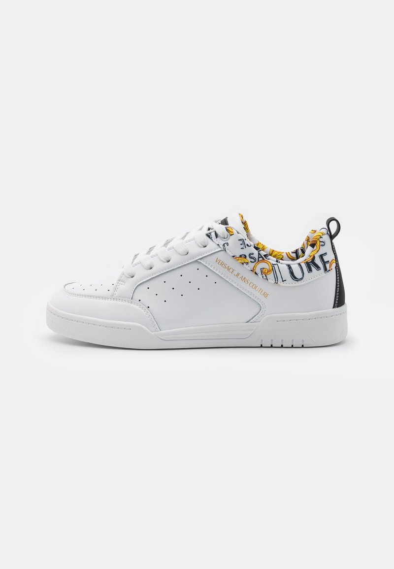 Baskets de tennis blanches avec des détails perforés, bout rond et col en tissu à motifs. Présente un logo "Versace Jeans Couture" et des accents noirs.