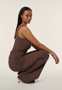 Top in cotone marrone e pantaloni a vita alta abbinati, con tasche e una vestibilità ordinata. Tessuto morbido e design affusolato con un marchio discreto.