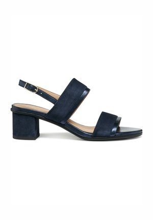Sandalia azul marino de ante con tacón grueso y correa ajustable con hebilla dorada, presenta dos tiras anchas sobre el pie y diseño de punta abierta.