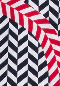 Mönstrad tyg med röda, svarta och vita zigzag ränder, med en upprepande geometrisk design och kontrasterande färger. Mjuk textur.