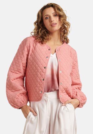 Roze gewatteerde jas met een ronde halslijn, zilveren drukknoopjes en pofmouwen. Gedragen over een lichte blouse en witte broeken.