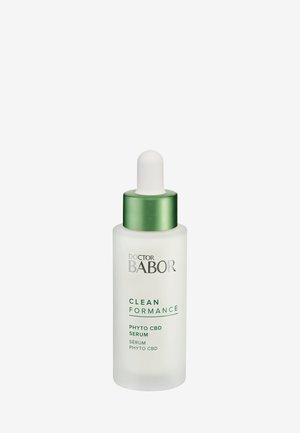 Bouteille de sérum en verre clair avec un compte-gouttes blanc et un capuchon vert. L'étiquette présente "Doctor Babor" et les détails du produit en texte vert.
