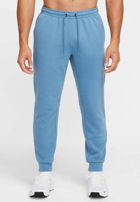 Light blue sweatpants made of soft fabric with a drawstring waistband, slim fit, and elastic cuffs at ankle. Worn with white sneakers.