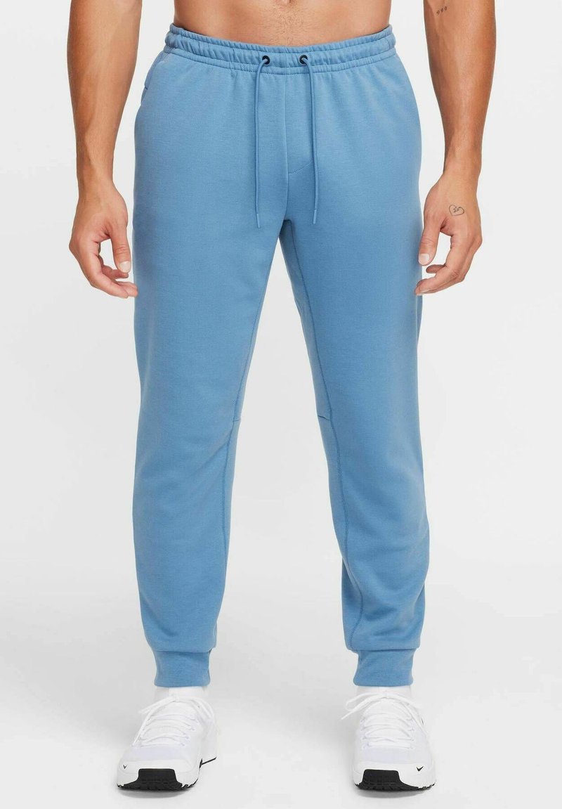 Light blue sweatpants made of soft fabric with a drawstring waistband, slim fit, and elastic cuffs at ankle. Worn with white sneakers.