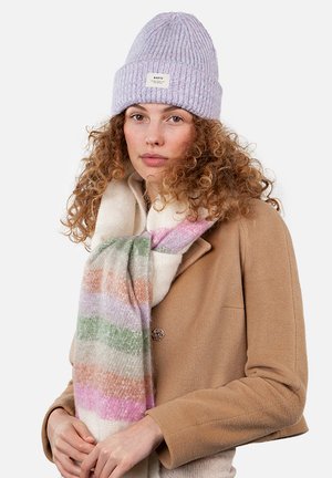 Gorro de punto acanalado en lavanda y una bufanda de rayas multicolores con tonalidades de rosa, verde y naranja, llevados sobre un abrigo marrón.