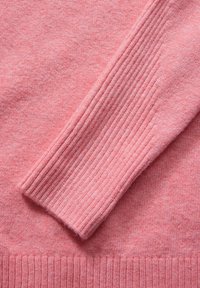 Różowy sweter z gładką strukturą i ściągaczami na rękawach. Miękka faktura z delikatnym melanżowym wzorem w całej powierzchni.