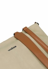 Borsa beige con manici in pelle marrone, caratterizzata da una superficie liscia e logo in rilievo. Design minimalista con due punti di aggancio per le tracolle.